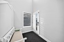 Entryway featuring a white door with a vertical glass panel, a window with horizontal blinds, and dark-toned flooring - 2415 194 Street Nw, Edmonton, AB 