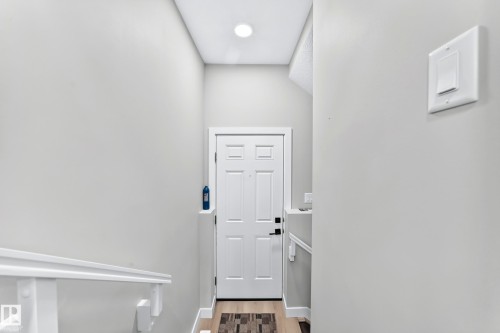 White panel door with black hardware, wood-finish flooring, and recessed ceiling lighting - 2415 194 Street Nw, Edmonton, AB 