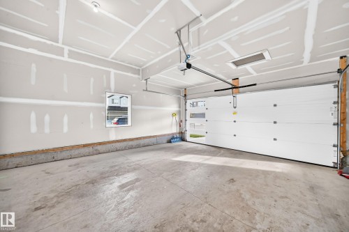 Unfinished interior walls, concrete flooring, automatic garage door opener, overhead lighting, and a single window - 2415 194 Street Nw, Edmonton, AB 
