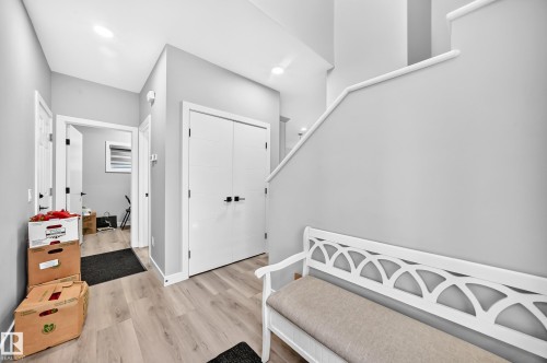 Light wood-finish flooring, white walls, white doors with dark hardware, and recessed ceiling lighting - 2415 194 Street Nw, Edmonton, AB 