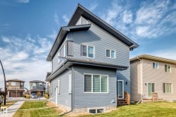 Modern exterior with blue horizontal siding, dark roofline, multiple windows, and a side entrance with wood stairs - 