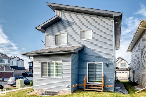 Contemporary exterior with blue siding, multi-level roofline, sliding glass door, and wooden stairs - 2415 194 Street Nw, Edmonton, AB 