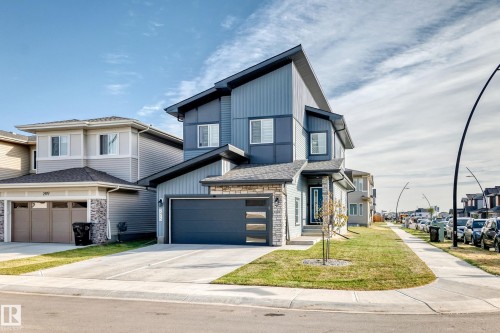 Contemporary facade with a dark gray garage door, stacked stone accents, and a covered entry - 2415 194 Street Nw, Edmonton, AB 