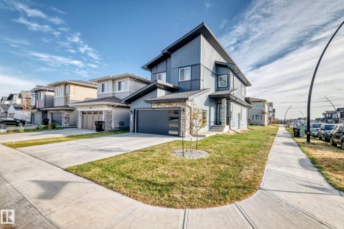Modern multi-story facade featuring siding and stone accents, an attached garage, and a concrete driveway - 2415 194 Street Nw, Edmonton, AB 