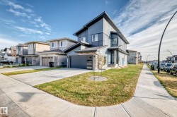 Modern multi-story facade featuring siding and stone accents, an attached garage, and a concrete driveway - 