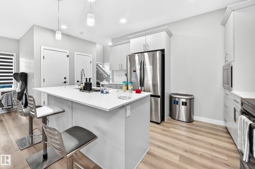 Kitchen island with integrated sink, stainless steel appliances, light wood-finish flooring, and recessed lighting - 2415 194 Street Nw, Edmonton, AB 