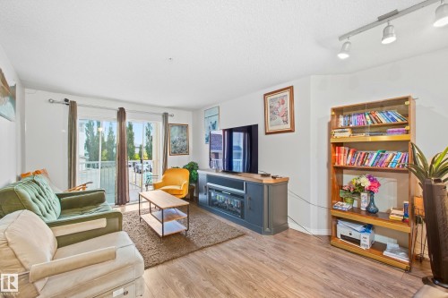 Wood-finish flooring, sliding glass patio door, track lighting, and white walls - #203 245 Edwards Dr Sw, Edmonton, AB 