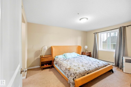 Warm neutral wall color complemented by broadloom carpeting - #203 245 Edwards Dr Sw, Edmonton, AB 