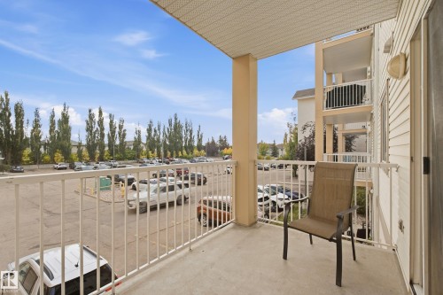 Private balcony with concrete flooring, white metal railing, and a textured ceiling - #203 245 Edwards Dr Sw, Edmonton, AB 