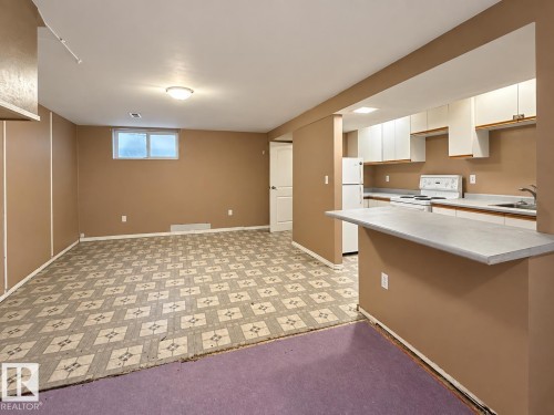Kitchenette with white cabinetry, a built-in electric range, and a refrigerator - 12204 40 Avenue Nw, Edmonton, AB 
