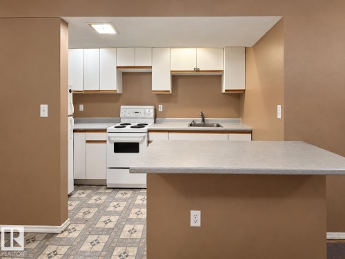 Modern kitchen featuring white cabinetry with ample storage, stainless steel appliances including a slide-in range and built-in microwave, granite countertops, and a spacious island with extended seating - 12204 40 Avenue Nw, Edmonton, AB 