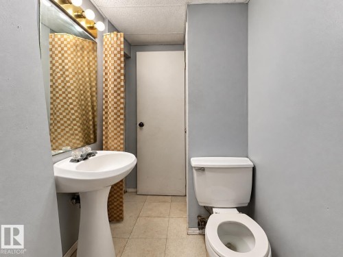 Pedestal sink with a coordinating white toilet, illuminated by a vanity light fixture - 12204 40 Avenue Nw, Edmonton, AB 