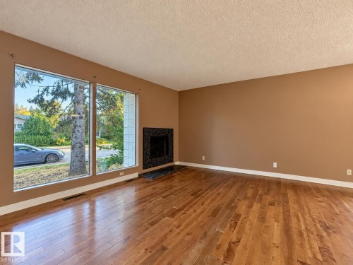 Hardwood flooring, expansive windows, built-in fireplace, tile hearth, and textured ceiling - 12204 40 Avenue Nw, Edmonton, AB 