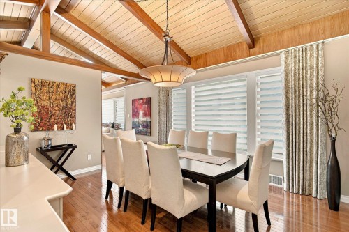 Vaulted ceiling with exposed wood beams, wood-finish flooring, multiple windows with horizontal blinds, and a built-in light fixture - 13862 Ravine Drive Nw, Edmonton, AB 