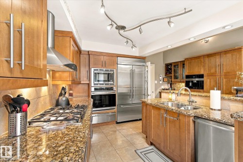 Kitchen featuring wood cabinetry, stainless steel appliances, granite countertops, a gas cooktop, and a double basin sink - 13862 Ravine Drive Nw, Edmonton, AB 