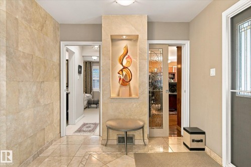 Tiled entryway with an illuminated inset niche, adjacent to a door with decorative glass paneling - 13862 Ravine Drive Nw, Edmonton, AB 