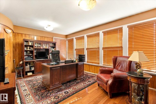 Hardwood flooring, wood paneling, multiple windows with wood blinds, built-in shelving, and an overhead light fixture - 13862 Ravine Drive Nw, Edmonton, AB 