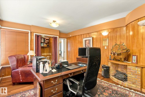 Wood paneling throughout, integrated brick fireplace, built-in shelving, wood-finish flooring, and a window with blinds - 13862 Ravine Drive Nw, Edmonton, AB 