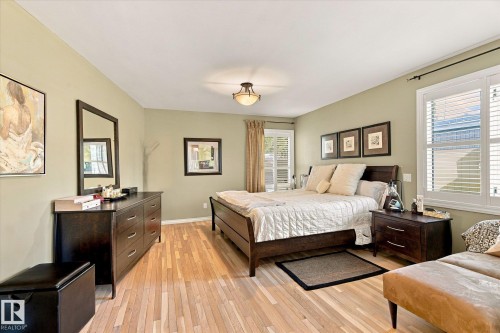 Natural wood-finish flooring, recessed lighting, and a window with white louvered shutters - 13862 Ravine Drive Nw, Edmonton, AB 