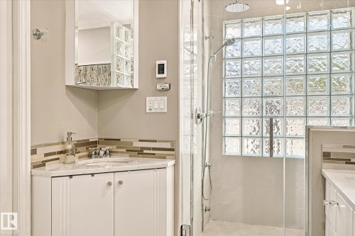 Corner vanity with an integrated sink and white cabinetry, complemented by a mosaic tile backsplash - 13862 Ravine Drive Nw, Edmonton, AB 