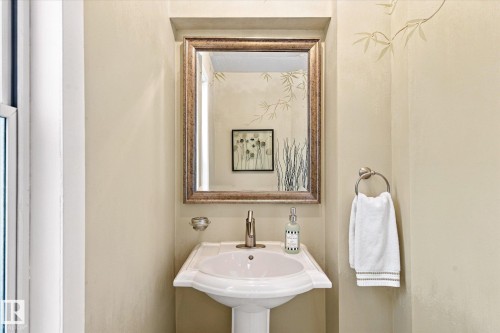 Pedestal sink with polished chrome faucet, decorative framed mirror, and wall-mounted towel ring - 13862 Ravine Drive Nw, Edmonton, AB 