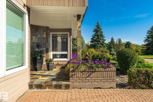 Stone veneer facade, covered entry, slate tile steps, brick-patterned paving, and a built-in brick planter - 13862 Ravine Drive Nw, Edmonton, AB 