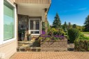 Stone veneer facade, covered entry, slate tile steps, brick-patterned paving, and a built-in brick planter - 13862 Ravine Drive Nw, Edmonton, AB 