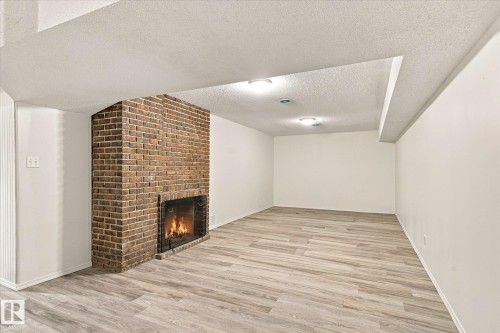 Brick fireplace with a hearth, wood-finish flooring, recessed lighting, and white painted walls - 13862 Ravine Drive Nw, Edmonton, AB 