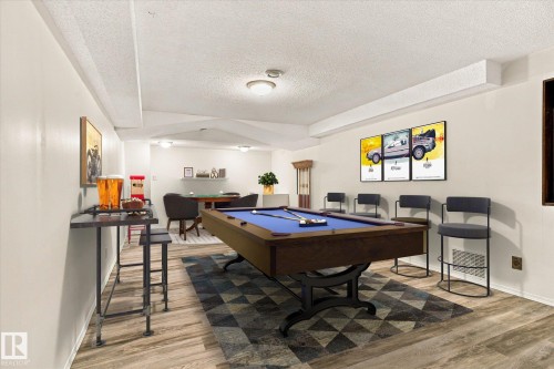 Recessed lighting throughout a spacious recreational room with wood-finish flooring - 13862 Ravine Drive Nw, Edmonton, AB 