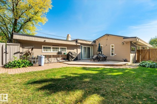 Expansive lawn area with a brick paver pathway, leading to a spacious deck surface - 13862 Ravine Drive Nw, Edmonton, AB 