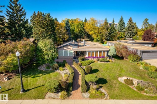 Single-story residence featuring a brick pathway, mature landscaping, and an attached garage - 13862 Ravine Drive Nw, Edmonton, AB 