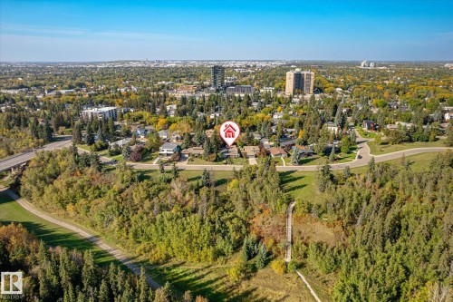 Residential area surrounded by mature trees, with visible roadways and distant urban structures - 13862 Ravine Drive Nw, Edmonton, AB 