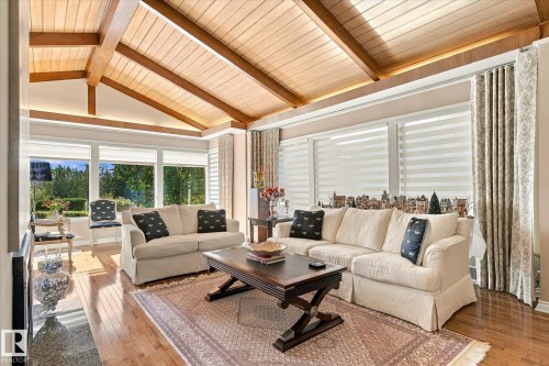 Vaulted wood-paneled ceiling with exposed beams, hardwood flooring, expansive windows, and full-length drapes - 13862 Ravine Drive Nw, Edmonton, AB 