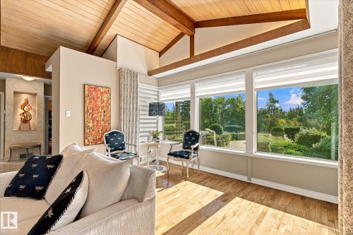 Vaulted wood-paneled ceiling with exposed beams, hardwood flooring, recessed wall niche, and multiple large windows overlooking exterior landscaping - 13862 Ravine Drive Nw, Edmonton, AB 