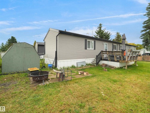 Rear exterior showcasing gray horizontal siding, a wooden deck with dark railing, and a green storage shed - 52 Evergreen Park Northwest, Edmonton, AB 