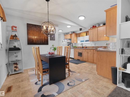 Open-concept kitchen and dining area featuring warm wood-finish cabinetry, a black kitchen faucet, and recessed lighting - 52 Evergreen Park Northwest, Edmonton, AB 