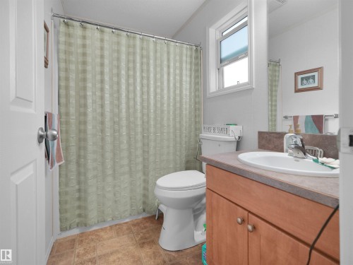 Bathroom featuring a vanity with a white basin sink, wood-finish cabinetry, and a window - 52 Evergreen Park Northwest, Edmonton, AB 