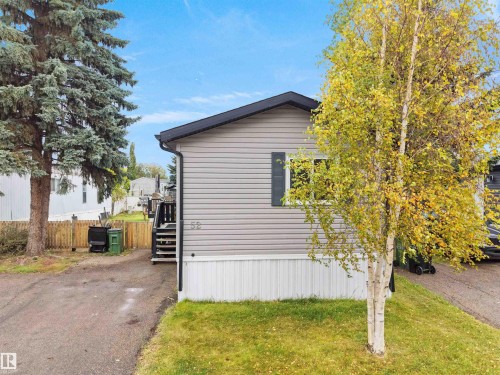 Siding exterior with dark shutters, dark roofline, wood fencing, and a paved driveway - 52 Evergreen Park Northwest, Edmonton, AB 