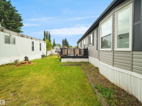 Expansive green lawn, raised wooden garden bed, dark wood deck with railing, and gray vinyl siding - 52 Evergreen Park Northwest, Edmonton, AB 