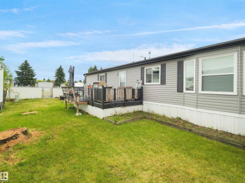 Expansive grassy yard with a multi-level wooden deck featuring a dark railing - 52 Evergreen Park Northwest, Edmonton, AB 