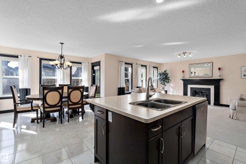 Kitchen island with a double basin sink, dark wood-finish cabinetry, and light-toned countertops - 11515 16 Avenue Sw, Edmonton, AB 