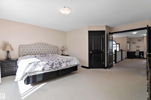 Neutral tone wall paint, light-colored carpet flooring, recessed ceiling light fixture, dark paneled doors, and an open entryway to an additional space - 11515 16 Avenue Sw, Edmonton, AB 