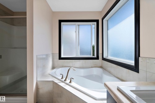 Built-in soaking tub with brushed nickel fixtures, tiled surround, and two opaque windows - 11515 16 Avenue Sw, Edmonton, AB 