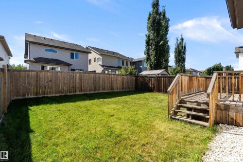 Expansive backyard featuring a manicured lawn, wood fencing, and a multi-level wood-finish deck with stairs - 11515 16 Avenue Sw, Edmonton, AB 