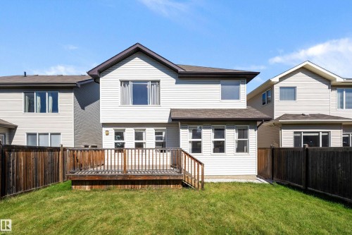 Spacious backyard featuring a wooden deck with railing, a grassy lawn, and horizontal privacy fencing - 11515 16 Avenue Sw, Edmonton, AB 