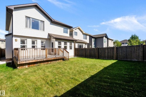 Expansive backyard featuring a manicured lawn, a wooden deck with railing, and a privacy fence - 11515 16 Avenue Sw, Edmonton, AB 