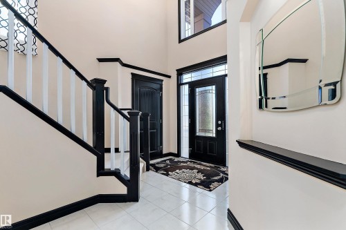 Two-story entry with tiled flooring, dark wood-finish trim, and a decorative front door with side lites - 11515 16 Avenue Sw, Edmonton, AB 