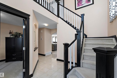 Central staircase featuring dark wood newel posts and handrails with white balusters - 11515 16 Avenue Sw, Edmonton, AB 
