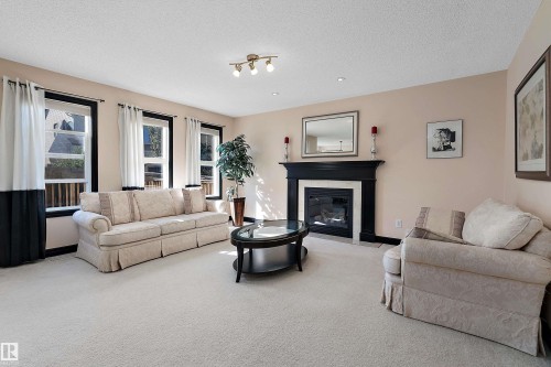Recessed lighting, track lighting, multiple windows with dark trim, and a fireplace with a dark mantel - 11515 16 Avenue Sw, Edmonton, AB 