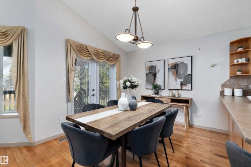Vaulted ceiling, wood-finish flooring, glass-paned French doors, built-in shelving, and a pendant light fixture - 1046 Blackburn Close Sw, Edmonton, AB 